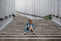 Joven pareja adulta en ropa casual en pasos concretos - foto de stock