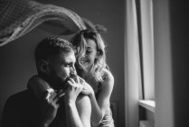 Portrait of young adult couple in bedroom interior, black and white — Stock Photo