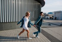 Vista lateral de correr jovem casal adulto em roupas casuais — Fotografia de Stock
