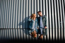 Distant view of young adult couple near modern style wall — Stock Photo