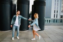 Distant view of smiling young adult couple against modern cityscape — Stock Photo