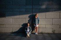 Young adult couple in casual clothing near gray wall — Stock Photo