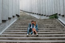 Молодая взрослая пара в повседневной одежде на конкретных ступенях — стоковое фото