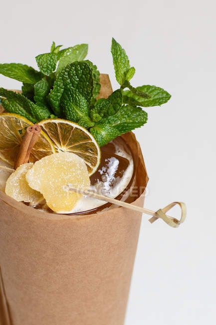 Vaso de bebida refrescante con rodajas de menta y cítricos envueltas en papel artesanal - foto de stock