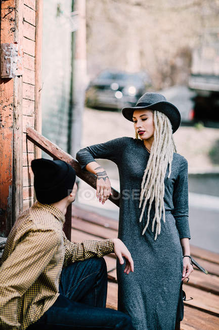 Woman with dreadlocks leaning on railing and looking down at boyfriend — Stock Photo