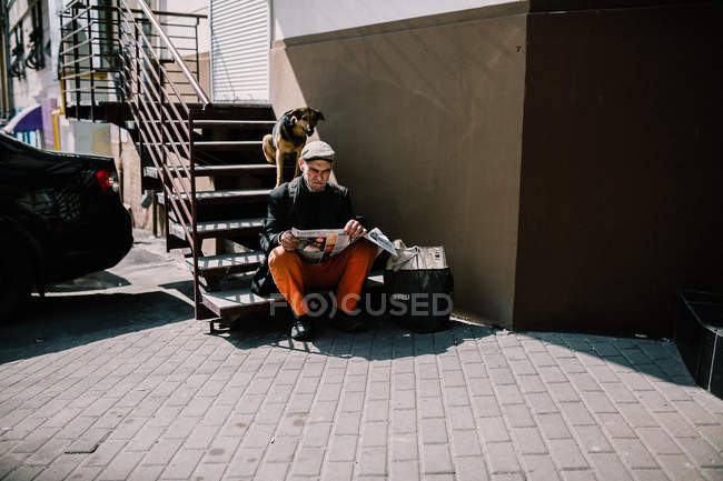 Київ, Україна-13 березня, 2018: безпритульні чоловік, сидячи на сходах і читання газет — стокове фото