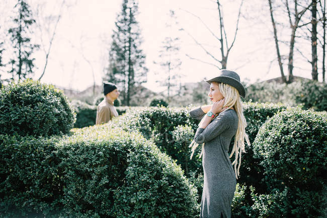 Молодая женщина с дредами с мужчиной, позирующим в изгороди в парке — стоковое фото