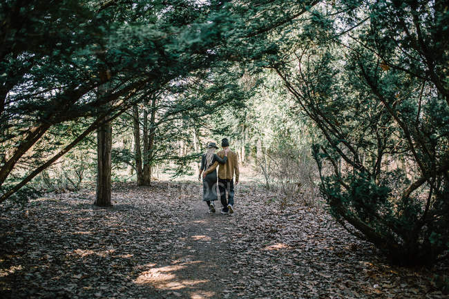 Blick von hinten auf junges Paar, das im Wald spaziert — Stockfoto