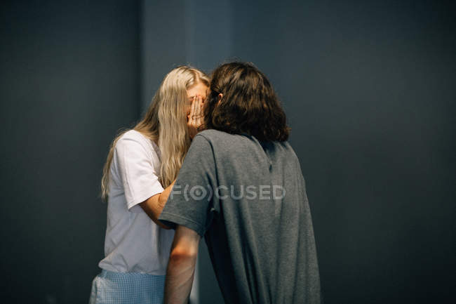 Giovane coppia nascondendo bacio con palme — Foto stock