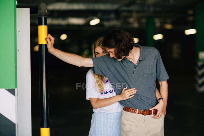 Chica rubia abrazando novio por detrás en el aparcamiento del centro comercial - foto de stock