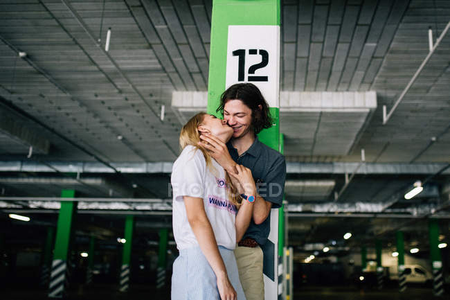 Casal rindo abraçando no estacionamento — Fotografia de Stock