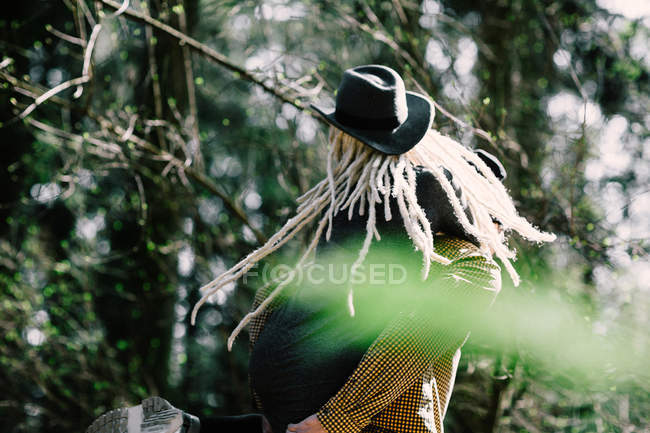 Задний вид девушки с дредами, принимающей поросёнка обратно на природу — стоковое фото