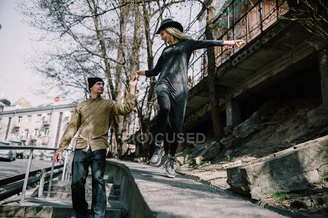 Cheerful blonde girl with dreadlocks and boyfriend walking at street scene — Stock Photo