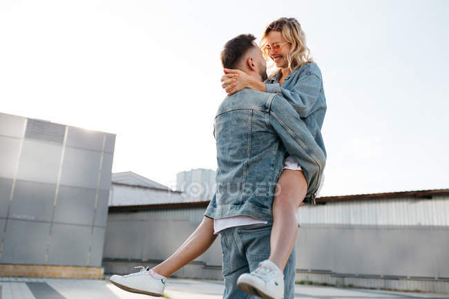 Jovem casal adulto abraçando na rua da cidade contra o céu — Fotografia de Stock