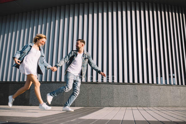 Side view of running young adult couple in casual clothing — Stock Photo