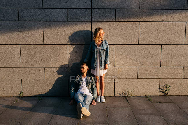 Молодая взрослая пара в повседневной одежде возле серой стены — стоковое фото