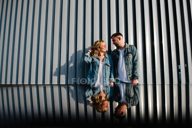 Vista lejana de pareja de adultos jóvenes cerca de la pared de estilo moderno - foto de stock