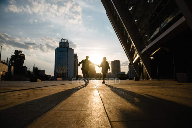 Vista cênica de silhuetas de casal adulto jovem contra a luz do pôr do sol — Fotografia de Stock