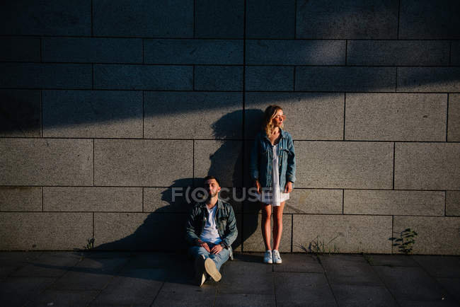 Jovem casal adulto em roupas casuais perto da parede cinza — Fotografia de Stock