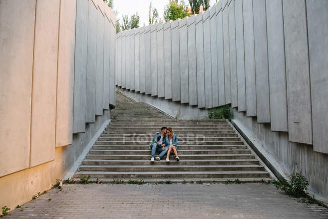 Молода доросла пара в повсякденному одязі на бетонних сходах — стокове фото