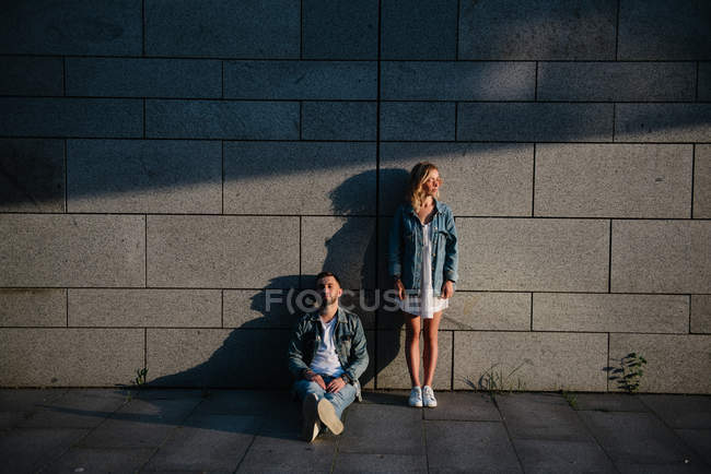 Jovem casal adulto em roupas casuais perto da parede cinza — Fotografia de Stock