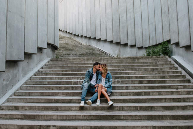 Молодая взрослая пара в повседневной одежде на конкретных ступенях — стоковое фото