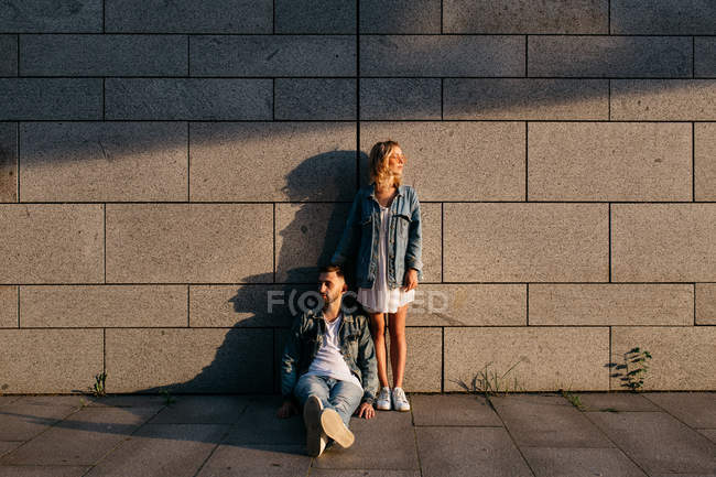 Joven pareja adulta en ropa casual cerca de la pared gris - foto de stock