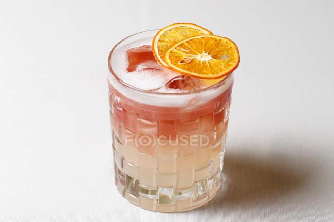 Вид сверху на алкогольный коктейль с сушеными ломтиками апельсина на столе — стоковое фото