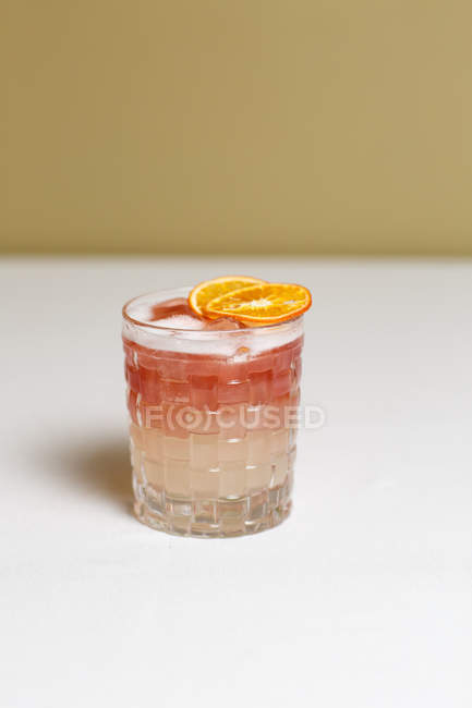Vista de cerca del cóctel de alcohol con rodajas secas de naranja sobre la mesa - foto de stock