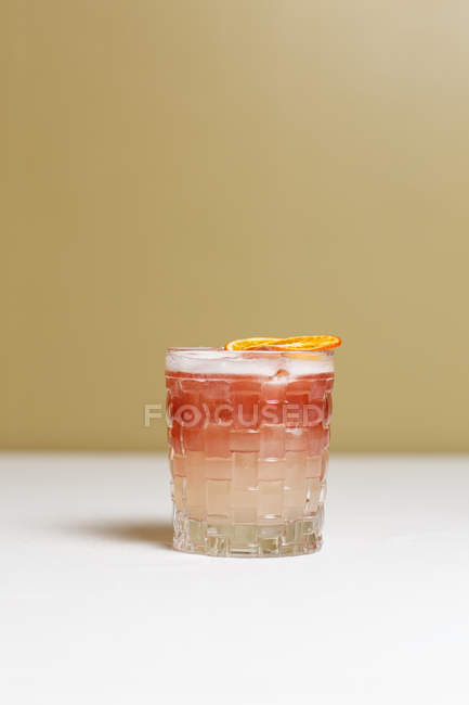 Крупный план алкогольного коктейля с сушеными ломтиками апельсина на столе — стоковое фото