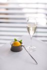 Nahaufnahme von gelbem Fruchteis mit Minzblättern bei einem Glas Wein auf weißem Tisch — Stockfoto