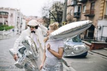 Stylish couple walking with silver balloons on city street — Stock Photo