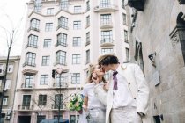 Frischvermählter Mann berührt und küsst Braut auf Stadtstraße — Stockfoto