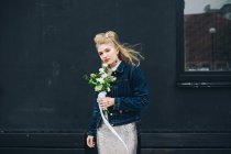 Mujer rubia joven en chaqueta de mezclilla con ramo de novia en la calle - foto de stock