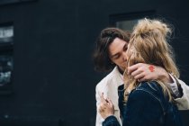 Jovem casal beijando na frente do edifício — Fotografia de Stock