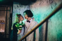 Newlywed couple embracing at staircase in grunge building — Stock Photo