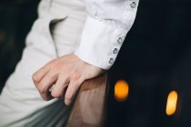 Close-up da mão masculina com manguito de camisa branca apoiada em trilhos de madeira — Fotografia de Stock