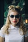 Portrait of stylish young woman in sunglasses with double-bun hairstyle — Stock Photo