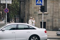 Elegante coppia di sposi in piedi su un incrocio urbano — Foto stock