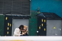 Urban scene of couple embracing and laughing against painted wall — Stock Photo