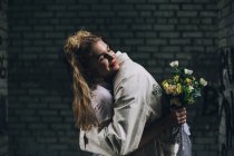 Felice sposa abbracciare sposo con bouquet da sposa nel backstreet urbano — Foto stock