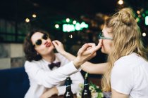 Giovane coppia in occhiali da sole toccare i volti e divertirsi al bar interno — Foto stock