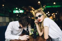 Stylish couple in sunglasses sitting in bar with beer — Stock Photo