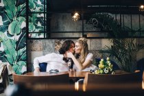 Giovane donna baciare l'uomo mentre beve da bottiglia in interno caffè — Foto stock