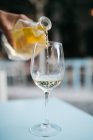 Image recadrée de la main masculine versant du vin blanc dans un verre à vin — Photo de stock