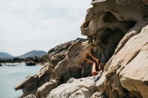Donna sdraiata sulla spiaggia vulcanica e libro di lettura, Paros, Mar Egeo, Cicladi, Grecia — Foto stock