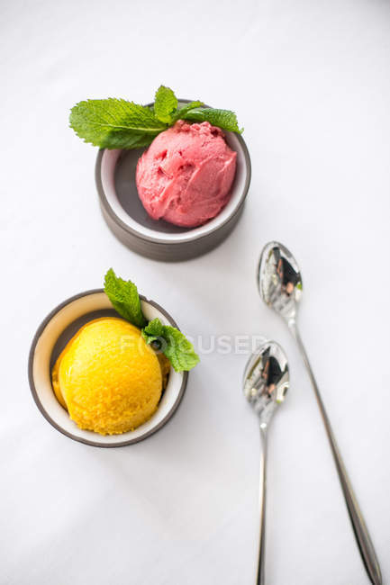 Вид сверху на два фруктовых мороженых с мятными листьями в мисках — стоковое фото