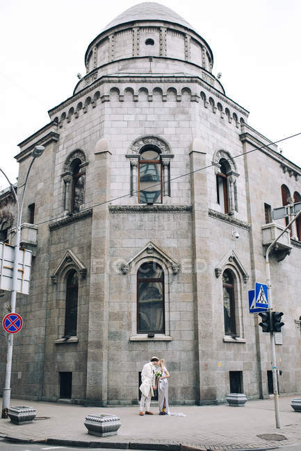 Casal recém-casado elegante em pé na encruzilhada urbana — Fotografia de Stock