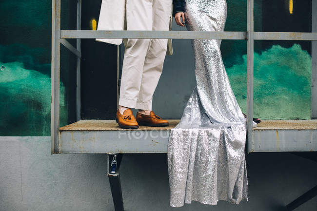 Vista recortada de pareja joven en traje blanco y vestido largo de plata - foto de stock