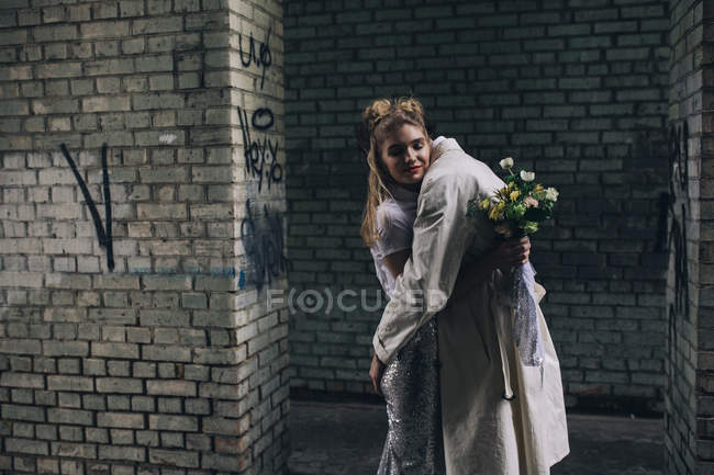 Scena urbana di coppia di sposi che si abbracciano davanti al muro di cinta — Foto stock